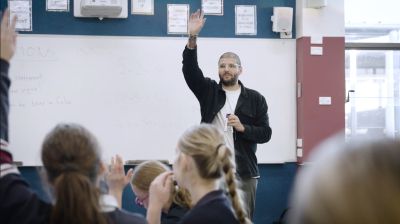 Zachary Fehily standing at the front of a classroom teaching students.