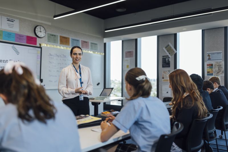 Elysia stands in front of her classroom, smiling as she explains the lesson.
