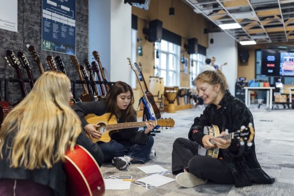 A music teacher and two students playing the guitar
