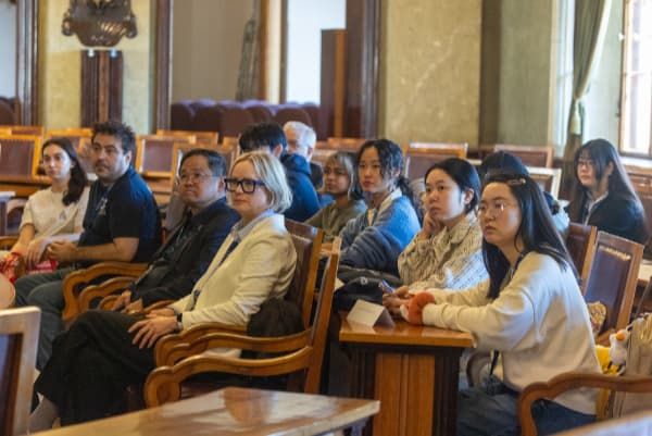 students seated in a theatre listening to a presentation 