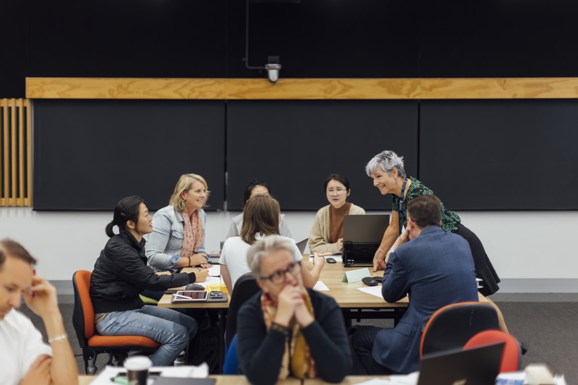 A teacher is speaking to a group of adults