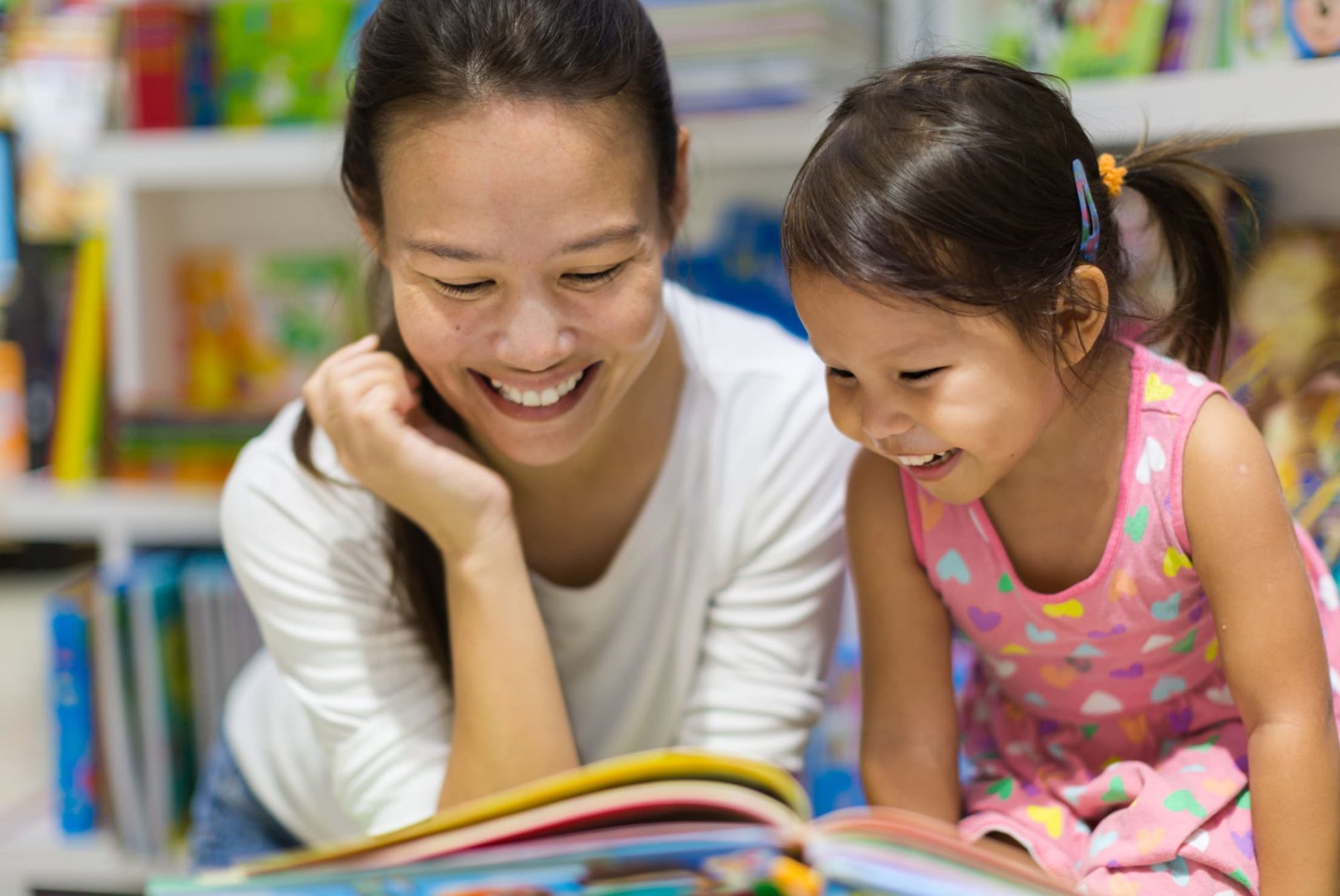 Teacher reading an educational book to her female student