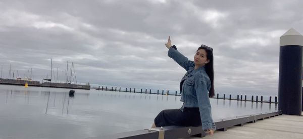 Mia sits on the dock in Geelong and turns to face the camera.