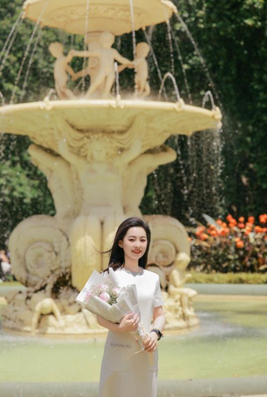 Jenny Ruan stands in front of the fountain outside the Royal Exhibition Building holding a bouquet of flowers.