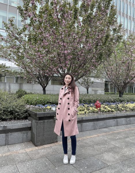 Cara stands in front of a flowering cherry blossom tree.