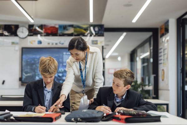 A teacher explaining something to a student while another listens