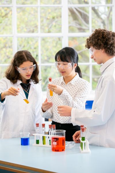 A teacher helps students conduct a mock science experiment.