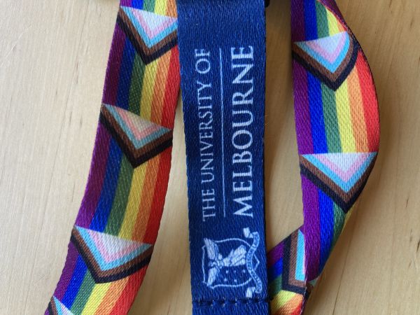 A photo of a Pride rainbow lanyard and with the University of Melbourne log