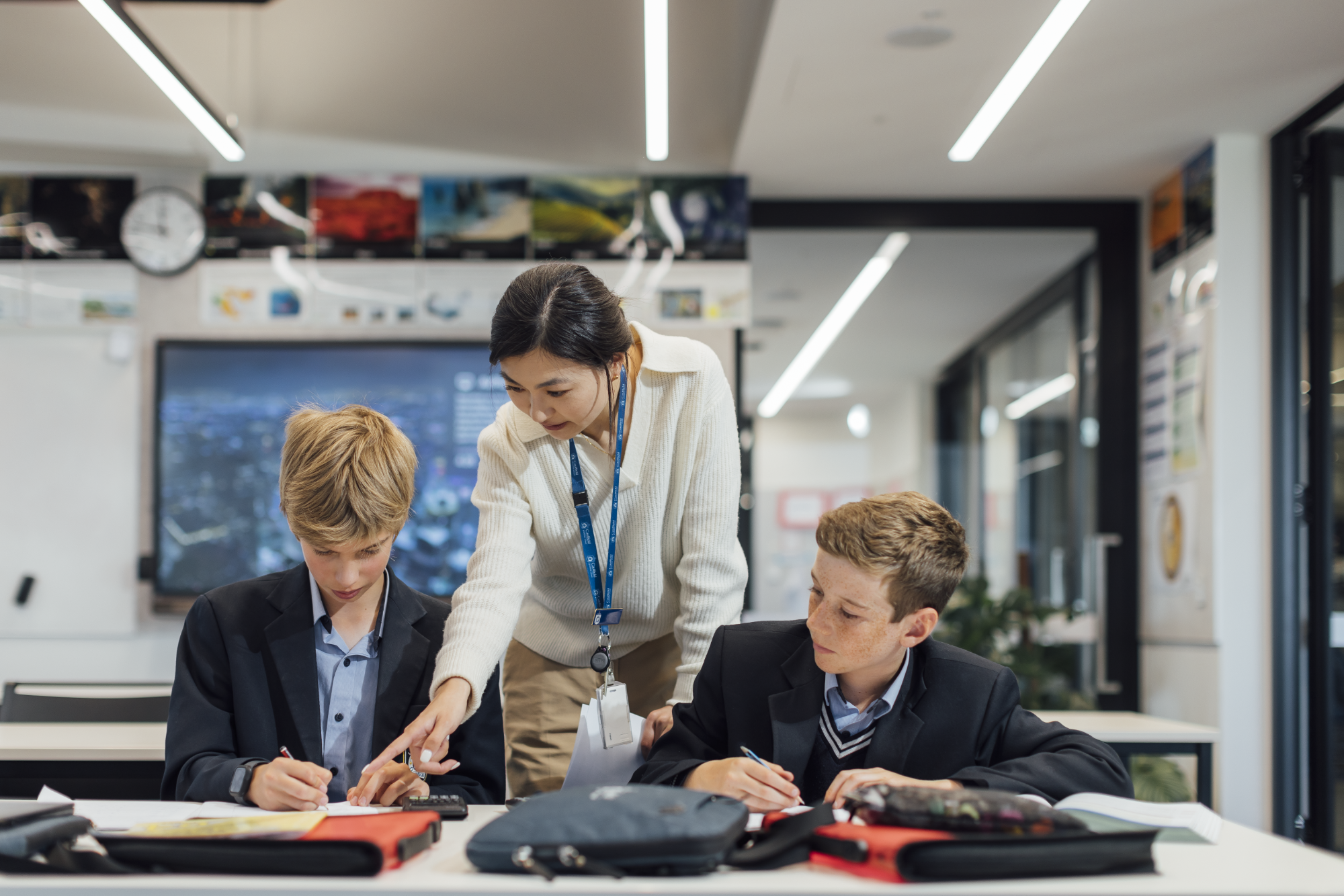 Student teacher teaching two young school boys